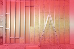 A wall under construction showing metal studs and exposed insulation with an aluminum stepladder standing in front.