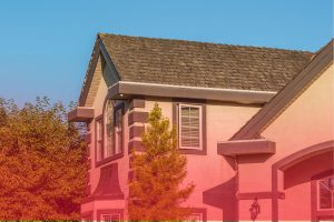 Exterior view showing the shingle roof and upper story of a residential house under a clear blue sky.